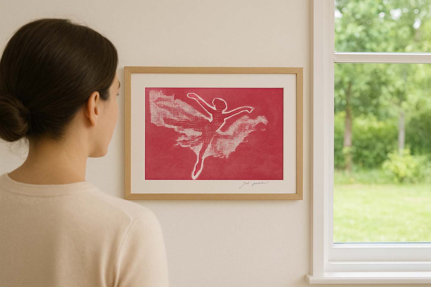 Woman looking at a framed artwork of a dancer on a red background by a window with greenery outside.