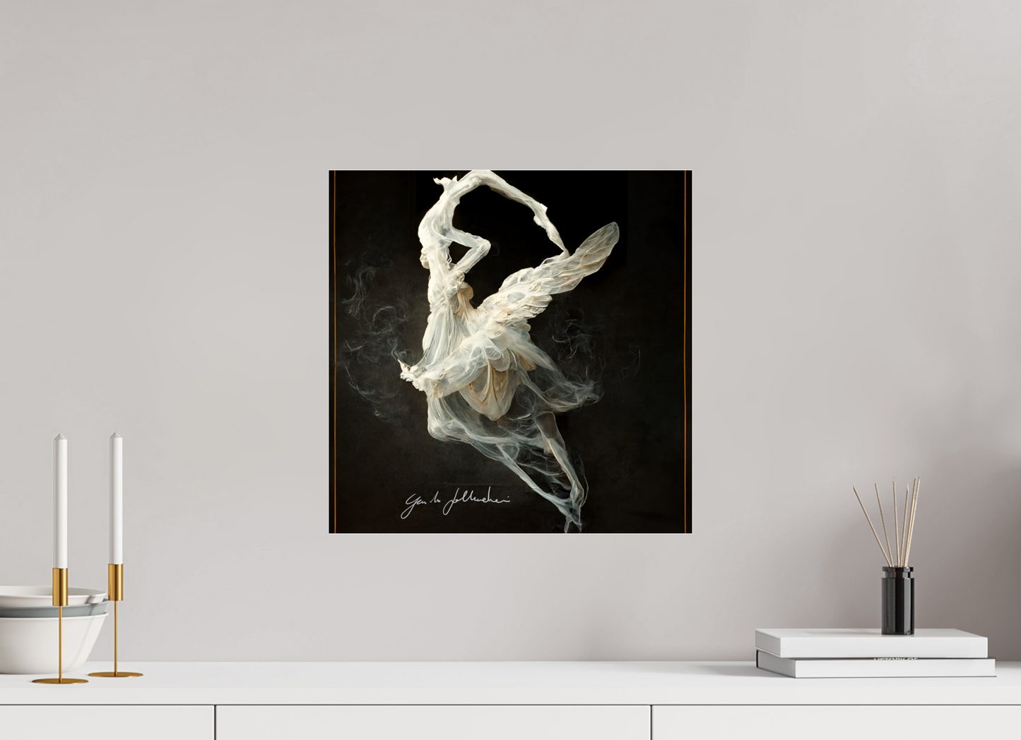 Abstract art of a winged figure on a black background, displayed on a wall above a white surface with decorative items.