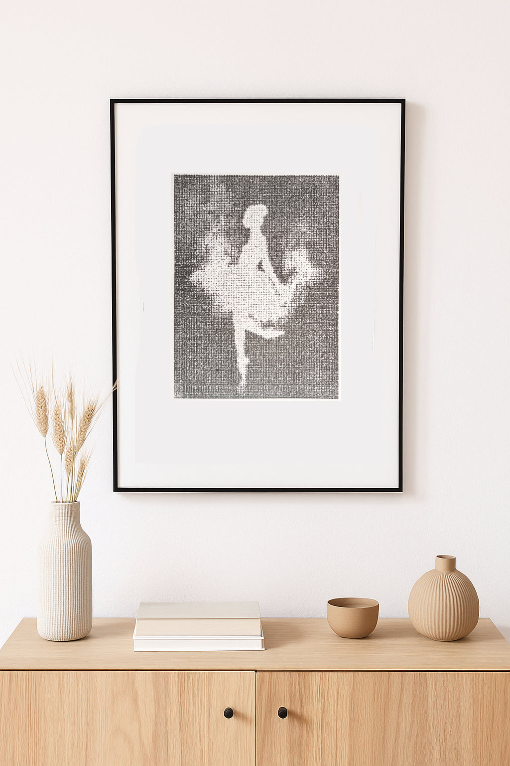 Framed artwork of a ballerina on a wall above a wooden cabinet with decorative items.